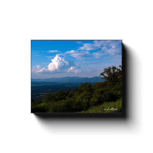 Gallery-wrapped canvas print featuring Virginia farmland, forested hills, distant Blue Ridge Mountains, and towering white clouds beneath a bright blue sky.