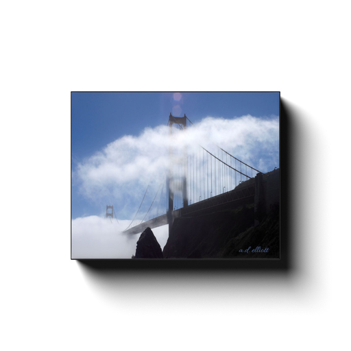 Gallery-wrapped canvas print featuring the Golden Gate Bridge partially hidden by white fog above the rocky San Francisco shoreline.
