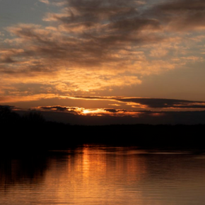 Golden sunset over Loch Lomond in Bella Vista, Arkansas, with dramatic clouds and warm light reflected across the lake.
