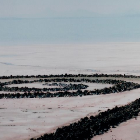 Close-up view of Spiral Jetty's winding rock formation extending into the salt flats of Utah's Great Salt Lake.