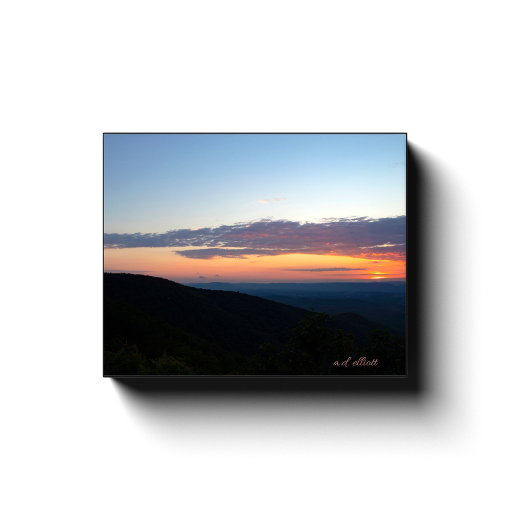 Gallery-wrapped canvas print featuring a mountain sunset with dark Blue Ridge silhouettes, glowing orange light, and a soft blue evening sky.