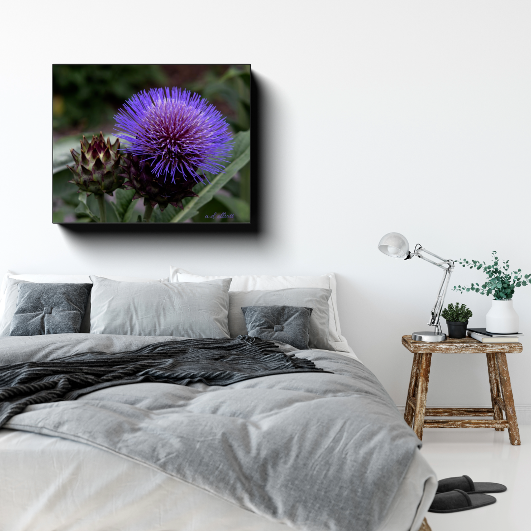 Gallery-wrapped canvas featuring a vivid purple thistle flower displayed above a gray bed in a bright, modern bedroom.