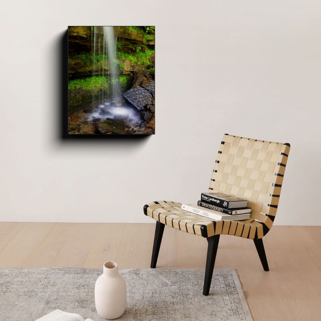 Twin Falls at Devil’s Den State Park canvas photograph displayed on a wall above a woven chair in a minimal room.