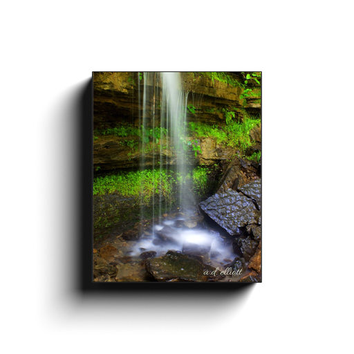 Gallery-wrapped canvas print featuring a soft waterfall, wet rocks, and lush green vegetation at Devil’s Den State Park in Arkansas.