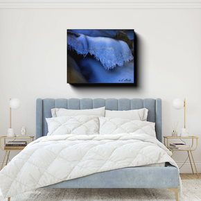 The Flow canvas photograph displayed above a light blue bed in a bright bedroom with gold-accented side tables.