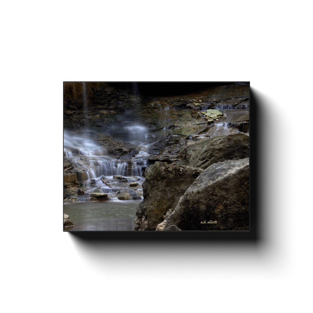 A long exposure photograph of a cascade on Pinion Creek in Bella Vista Arkansas. Taken by the photographer a.d. elliott - Take the Back Roads #TaketheBackRoads  Printed on high quality, artist grade stock and folded around a lightweight frame to give them a gorgeous, gallery ready appearance. With acid free ink that will last without fading or chipping, Features a scratch-resistant UV coating. Wipes clean easily with a damp cloth or to remove dust, vacuum gently using a soft brush attachment.