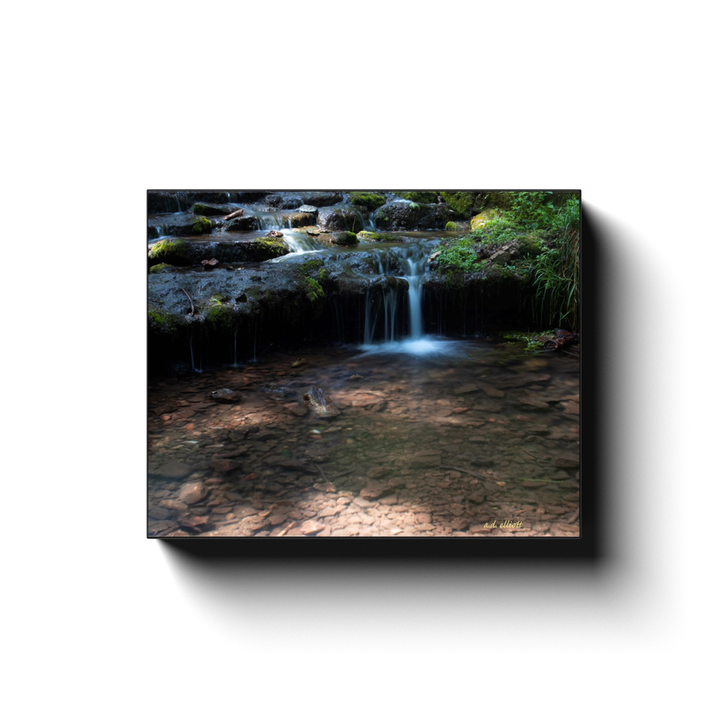 A long exposure photograph of a small cascade on Parks Spring in Bentonville Arkansas. Taken by the photographer a.d. elliott.  Printed on high quality, artist-grade stock and folded around a lightweight frame to give them a gorgeous, gallery-ready appearance. With acid-free ink that will last without fading or chipping, Features a scratch-resistant UV coating. Wipes clean easily with a damp cloth or to remove dust, vacuum gently using a soft brush attachment.
